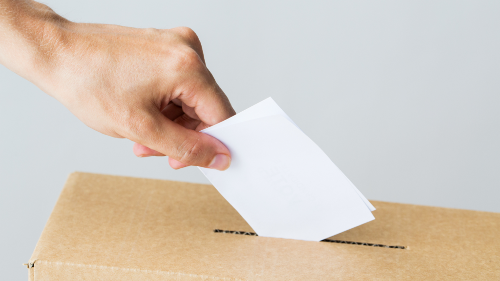 Ręka wkładająca kopertę do urny wyborczej