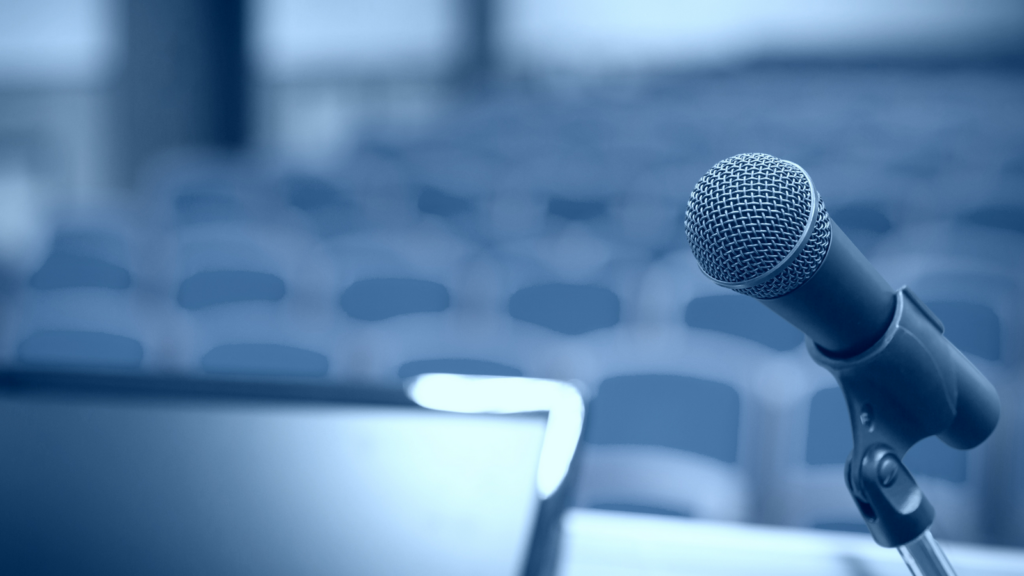 Mikrofon, w tle sala konferencyjna